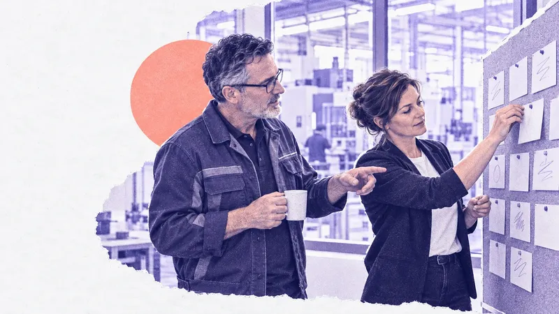 Eine Marketingleiterin heftet eine Karte an eine Pinnwand, ein Kollege in Arbeitsjacke zeigt auf eine andere Karte, dahinter eine Fertigungshalle
